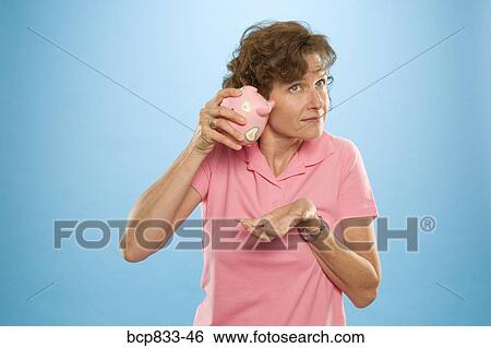 Woman trying to get money out of a piggy bank View Large Photo Image Stock Photograph - Woman trying to get money out of a piggy bank. Fotosearch