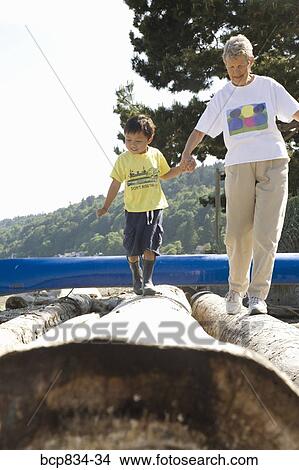 Woman walking on logs with her grandson View Large Photo Image Picture - Woman walking on logs with her grandson. Fotosearch