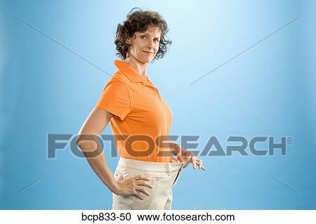 Stock Image - Woman wearing loose pants to show weight loss. Fotosearch