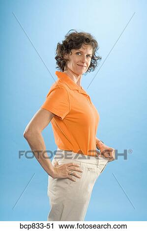 Woman wearing loose pants to show weight loss View Large Photo Image Stock Image - Woman wearing loose pants to show weight loss. Fotosearch