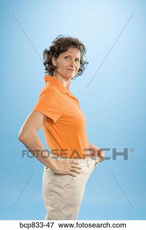 Woman wearing loose pants to show weight loss View Large Photo Image Stock Photo - Woman wearing loose pants to show weight loss. Fotosearch