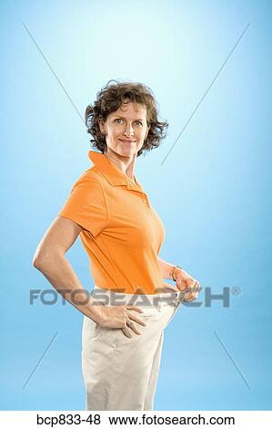Woman wearing loose pants to show weight loss View Large Photo Image Stock Photo - Woman wearing loose pants to show weight loss. Fotosearch