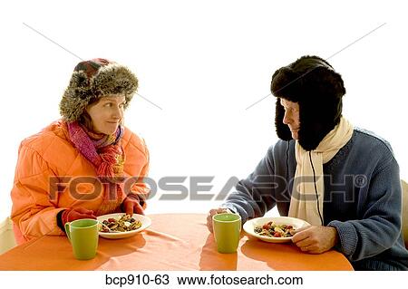 Stock Image - Couple dressed in winter apparel eating breakfast together. Fotosearch