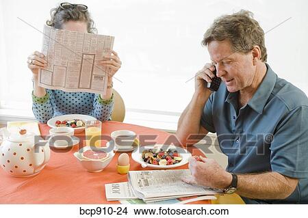 Picture - Couple having breakfast and checking newspaper classifieds. Fotosearch