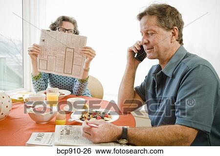 Stock Photograph - Couple having breakfast and checking newspaper classifieds. Fotosearch