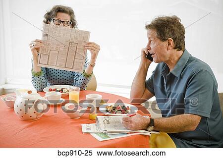 Stock Photography - Couple having breakfast and checking newspaper classifieds. Fotosearch