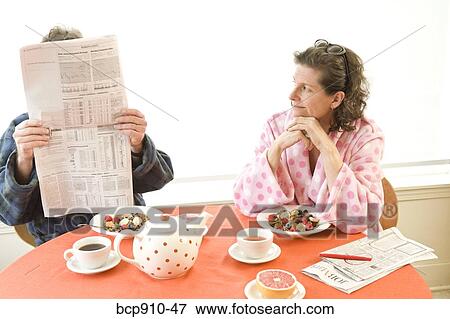 Stock Photo - Couple having breakfast and reading newspaper. Fotosearch