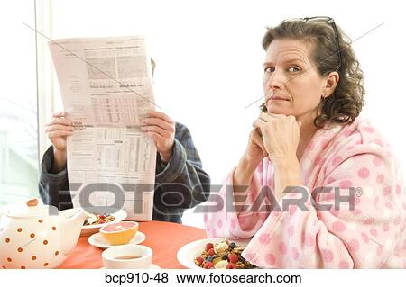 Couple having breakfast and reading newspaper View Large Photo Image Stock Photo - Couple having breakfast and reading newspaper. Fotosearch