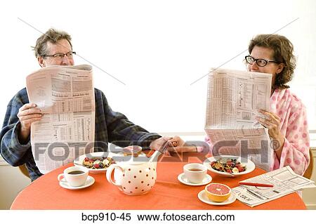 Stock Photography - Couple having breakfast and reading newspaper together. Fotosearch