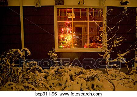 Stock Photograph - House in winter with Christmas Tree visible in window. Fotosearch