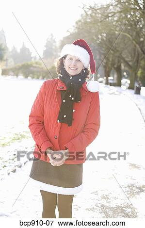 Smiling woman in a park wearing a Christmas hat View Large Photo Image Stock Photo - Smiling woman in a park wearing a Christmas hat. Fotosearch