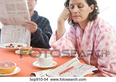 Tired woman with her husband at breakfast looking at classifieds View Large Photo Image Picture - Tired woman with her husband at breakfast looking at classifieds. Fotosearch