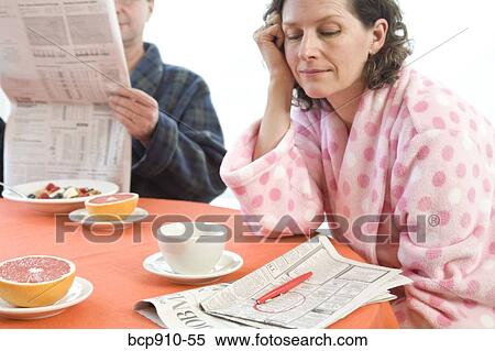 Stock Photography - Tired woman with her husband at breakfast looking at classifieds. Fotosearch
