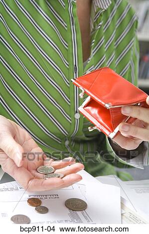 Picture - Woman emptying coins from a coin purse. Fotosearch