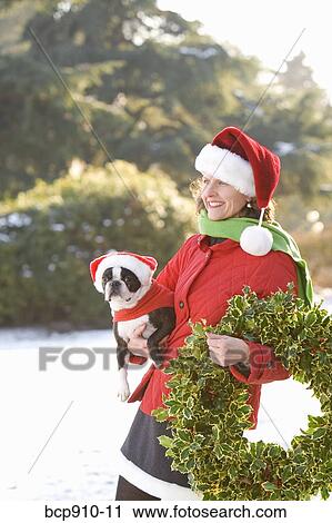 Woman in a park holding a Christmas wreath and a dog View Large Photo Image Stock Image - Woman in a park holding a Christmas wreath and a dog. Fotosearch