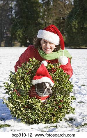 Woman in a park with a dog wearing a Christmas wreath View Large Photo Image Stock Image - Woman in a park with a dog wearing a Christmas wreath. Fotosearch