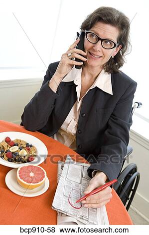 Woman in a wheelchair at breakfast talking on phone View Large Photo Image Stock Photo - Woman in a wheelchair at breakfast talking on phone. Fotosearch