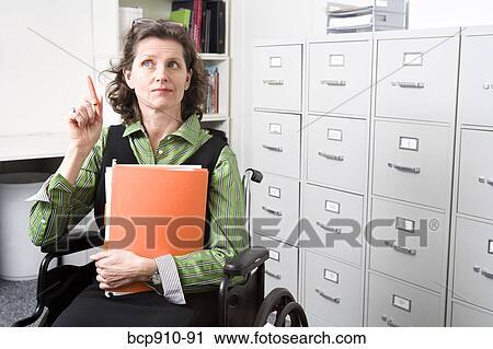 Stock Image - Woman in wheelchair holding files. Fotosearch