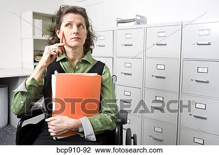 Stock Image - Woman in wheelchair holding files. Fotosearch