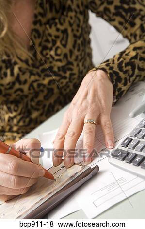 Stock Photo - Woman writing a check and paying bills. Fotosearch