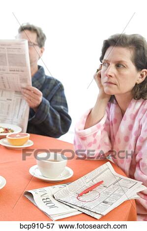 Worried woman with her husband at breakfast looking at newspaper View Large Photo Image Stock Photo - Worried woman with her husband at breakfast looking at newspaper. Fotosearch