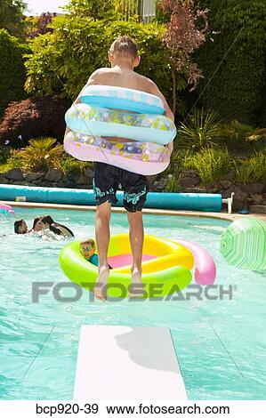Boy wearing rings jumping into pool View Large Photo Image Stock Photo - Boy wearing rings jumping into pool. Fotosearch