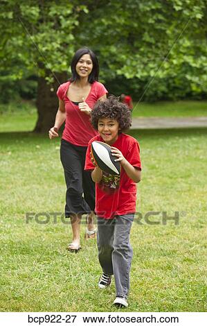 Boy with football running from mother View Large Photo Image Stock Photo - Boy with football running from mother. Fotosearch