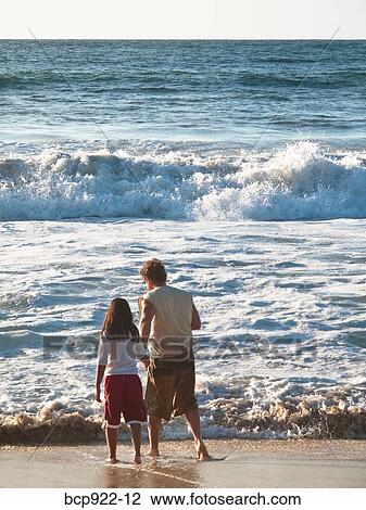 Man and girl looking at surf View Large Photo Image Stock Image - Man and girl looking at surf. Fotosearch