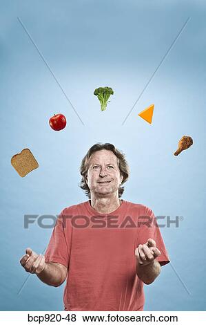 Stock Photo - Man juggling different foods. Fotosearch