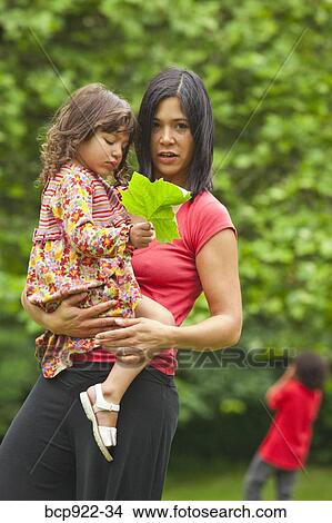 Picture - Mother holding young daughter outdoors. Fotosearch