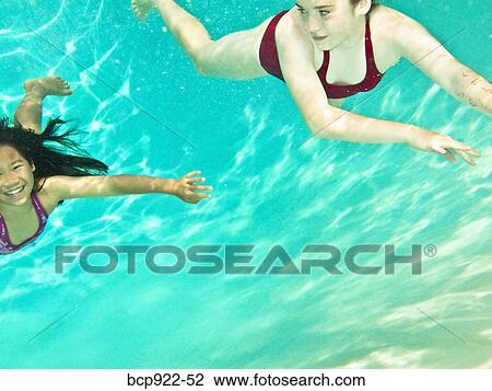 Two girls swimming under water View Large Photo Image Stock Image - Two girls swimming under water. Fotosearch