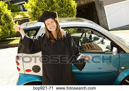 Stock Image - Woman in cap and gown with smart car. Fotosearch