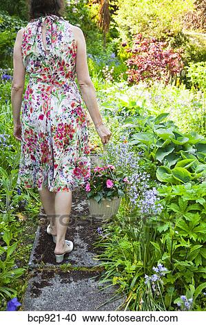 Woman in flowered dress in garden View Large Photo Image Stock Image - Woman in flowered dress in garden. Fotosearch