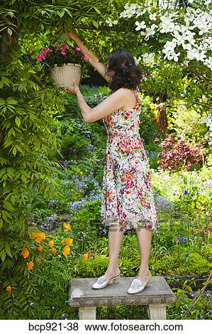 Woman in flowered dress in garden View Large Photo Image Stock Photo - Woman in flowered dress in garden. Fotosearch