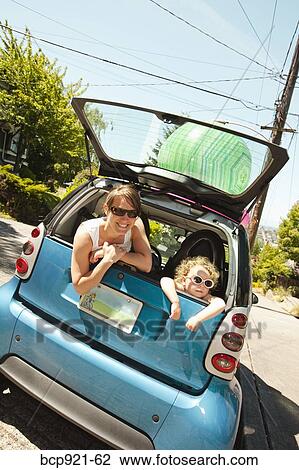 Stock Image - Woman with girl in back of smart car. Fotosearch