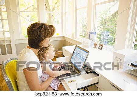 Woman with young child in home office View Large Photo Image Stock Photo - Woman with young child in home office. Fotosearch