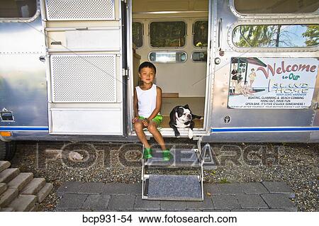 Picture - Boy and dog sitting in camper doorway. Fotosearch