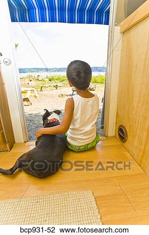Stock Image - Boy and dog sitting in camper doorway. Fotosearch