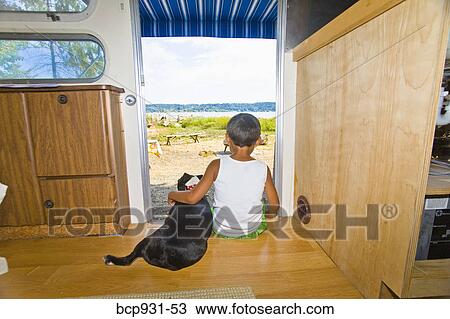 Boy and dog sitting in camper doorway View Large Photo Image Stock Image - Boy and dog sitting in camper doorway. Fotosearch