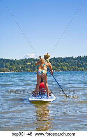 Stock Photo - boy and girl on paddle board. Fotosearch