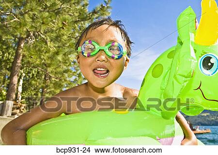 Picture - boy with dragon floatie and goggles. Fotosearch