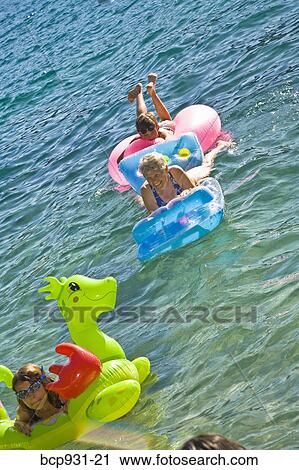 Stock Image - children and grandmother on floaties in lake. Fotosearch