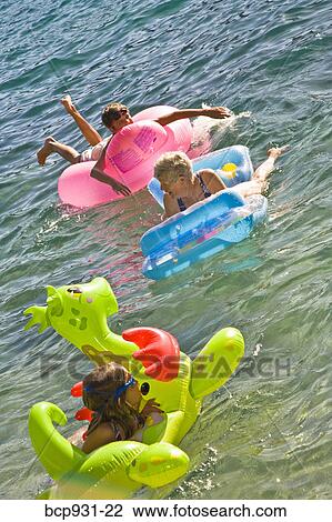 Stock Image - children and grandmother on floaties in lake. Fotosearch
