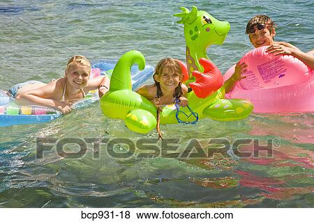 Stock Photo - children on floaties in lake. Fotosearch