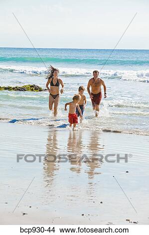 Picture - family running on beach in mexico. Fotosearch