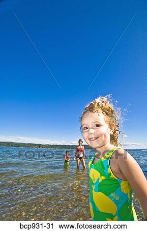 Stock Image - woman and children wading on a beach. Fotosearch
