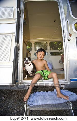 Boy sitting in door of camper with dog View Large Photo Image Stock Image - Boy sitting in door of camper with dog. Fotosearch