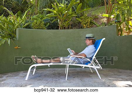 man reading e-book on chaise outdoors View Large Photo Image Stock Image - man reading e-book on chaise outdoors. Fotosearch