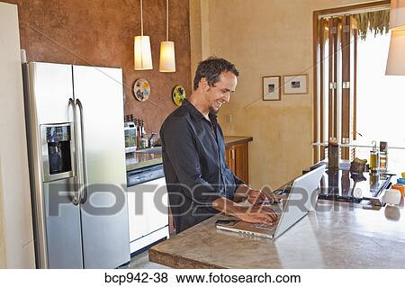 man working on laptop in kitchen View Large Photo Image Stock Photo - man working on laptop in kitchen. Fotosearch