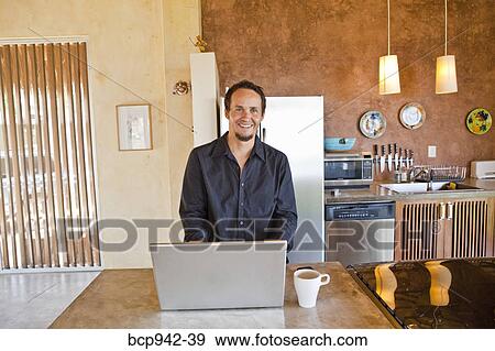 man working on laptop in kitchen View Large Photo Image Stock Photo - man working on laptop in kitchen. Fotosearch